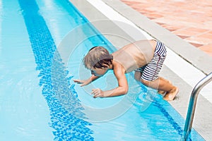 Happy boy kid jumping in the pool