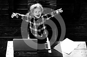 Happy boy kid in office with laptop, phone, paper sheet