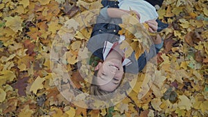 Happy boy lays on autumn leaves