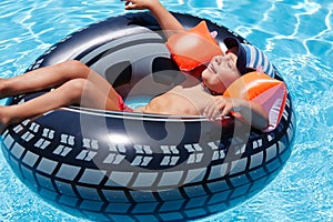 Happy boy lies with eyes closed on wheel in pool