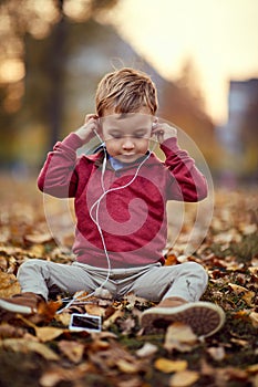 Happy boy listen music on smartphone. Family, childhood, season and people concept