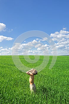 Happy boy looking to the sun on green field