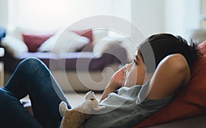 Happy boy lying on bean bag looking up watching cartoon on TV. Child resting in living room with brightlight shining from window