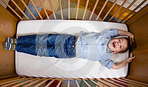 Happy boy lying in a cot with arms and legs