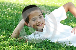 Happy boy lying on green grass