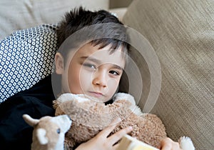 Happy boy lying on sofa looking up at camera with smiling face,Positive Child resting in living room with bright light shining