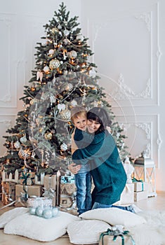 Happy boy with mather near Christmas tree