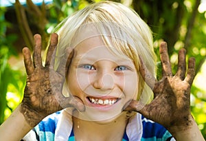 Happy boy outdoors with dirty hands