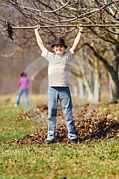 Happy boy pausing from raking leaves