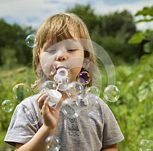 Happy Boy play in bubbles in field sunny summer day