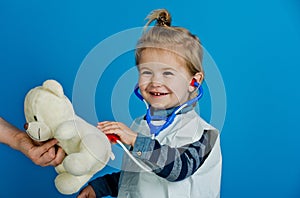 Happy boy play veterinarian with teddy bear in mothers hand