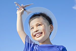 Happy boy playing a airplane toy with blue sky