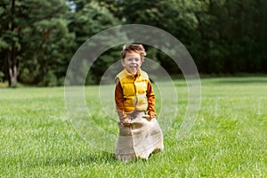 happy boy playing bag jumping game at park