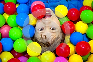 Happy boy playing in colorful balls. Happy child playing at colorful plastic balls playground high view