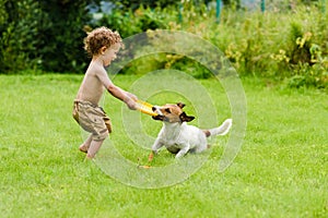 Happy boy playing with dog active game on lawn photo