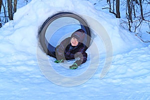 Happy boy playing in a snow tunnel.