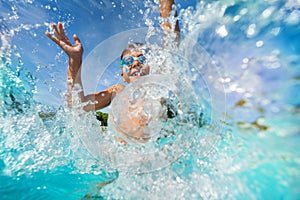 Happy boy playing and splashing in swimming pool