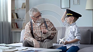 Happy boy playing with toy airplane, grandfather former pilot proud of grandson