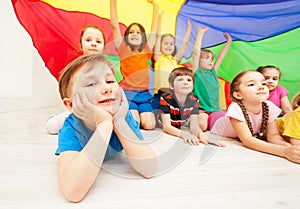 Happy boy playing under parachute with friends