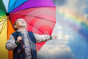 Happy boy portrait with bright rainbow umbrella