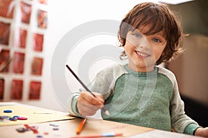 Happy boy, portrait and drawing with color for creativity, learning or education at home. Young child with smile and