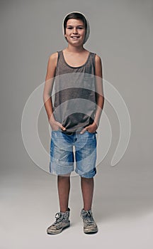 Happy boy, portrait and fashion with style in denim shorts or jeans on a gray studio background. Male person, child or