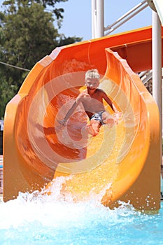 happy boy quickly going on the orange water slide