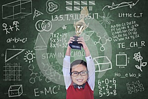 Happy boy raising trophy in class