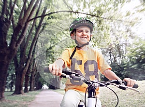 Happy boy ride a bicycle in city park