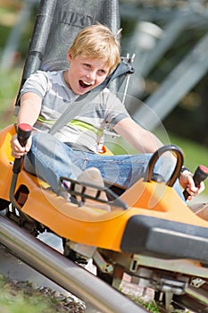 Happy boy riding at bobsled coaster rail trac