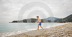 Happy boy run to the sea. Alone child have fun on beach, run by sea water pool. Active family lifestyle, kids outdoor
