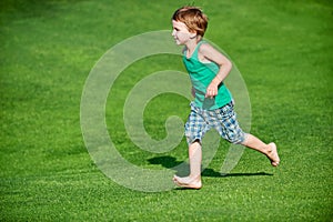 Happy boy running at the green golf course at sunny day