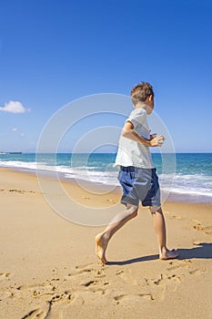 Happy boy running and playing on the summer beach. Young teenager relax and having fun in summer holiday vacation travel