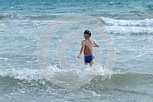 Happy boy runs into sea to swim