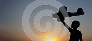 Happy Boy runs with a toy airplane on a field in the sunset light. Children play toy airplane. teenager dreams of flying and