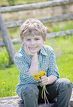 Happy Boy sitting on bench with bouquet of fresh picked flowers