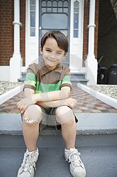 Happy Boy Sitting On Front Steps Of House