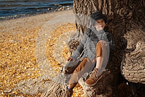 Happy boy sitting on the tree at the beach