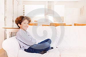 Happy boy sitting on white sofa in the living room