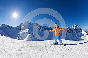 Happy boy in ski mask with arms apart skiing alone