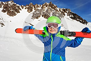 Happy boy with ski on shoulders over mountain rock