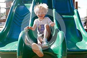 Happy boy sliding down a slide