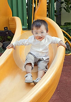 Happy boy sliding down slide