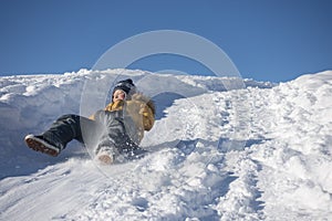 Happy boy sliding down snow hill on sled outdoors in winter, sledging and season concept