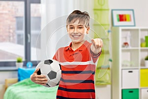 happy boy with soccer ball pointing to you at home