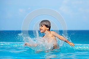 Happy boy splashing water around him in pool