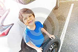 Happy boy standing next to the car with spare tire