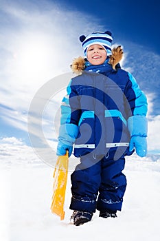 Happy boy standing with sled