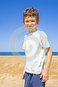 Happy boy standing on the summer beach. Young teenager relax and having fun in summer holiday vacation travel.