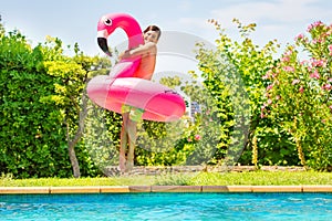 Happy boy with swim toy jumping in swimming pool